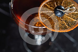 The Boulevardier Cocktail with orange chips on top. On a bar desk