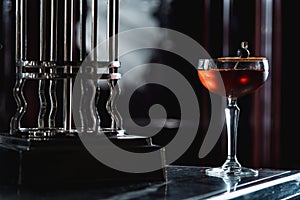 The Boulevardier Cocktail with orange chips on top. On a bar desk