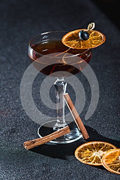 The Boulevardier Cocktail with orange chips on top. On a bar desk