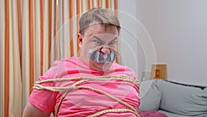 Bound man with mouth taped shut focuses thoughts, breaks ropes, frees himself