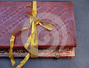 Bound notebook in leather and tied with a gold ribbon