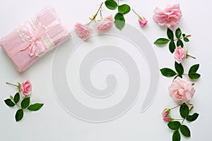 Bouquet of beautiful pink roses and gift in pink packing on white background.Top view.Copy space