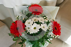 A bouquet of beautiful red gerberas and white chrysanthemums in a vase. A birthday gift