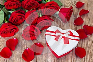 Bouquet of beautiful red roses on a wooden background with red heart shaped gift boxt