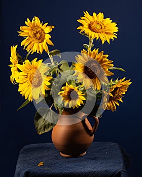 Bouquet beautiful Sunflowers in ceramic jar on a blue