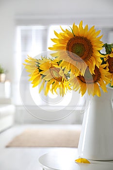 Bouquet of beautiful sunflowers in vase on table indoors