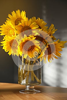 Bouquet of beautiful sunflowers in vase on table indoors