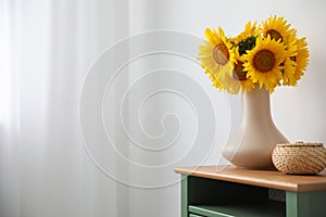 Bouquet of beautiful sunflowers and wicker basket on table indoors. Space for text