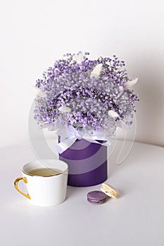Bouquet of beautiful violet flowers in box with tea and macaroons