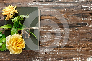 Bouquet of beautiful yellow roses and stack of old vintage books on wooden background. Congratulation or invitation to the holiday