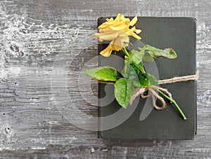 Bouquet of beautiful yellow roses and stack of old vintage books on wooden background. Congratulation or invitation to the holiday