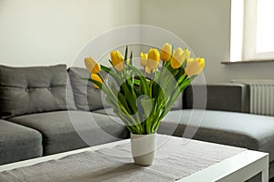 Bouquet of beautiful yellow tulips on table in living room