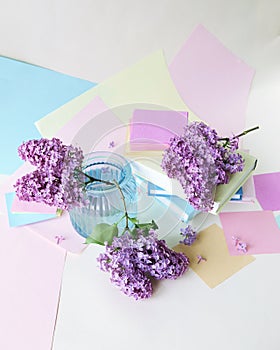Bouquet of blooming lilac flowers in a glass vase, books, school supplies