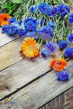 Bouquet of blue cornflowers and calendula on vintage wooden boar