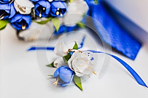 A bouquet of the bride from white and blue roses and wedding rings from gold
