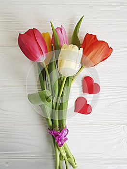 bouquet of colored tulips valentine white wooden background two red hearts