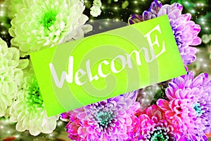 Bouquet of colorful flowers and green greeting card with Welcome text. Hotel reception