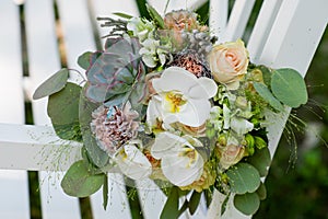 A bouquet of colorful flowers lies on a white bench.