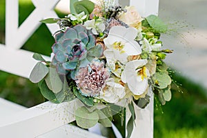 A bouquet of colorful flowers lies on a white bench.