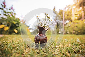 Bouquet of colorful wild wild flowers in a broken clay pot laid on the grass