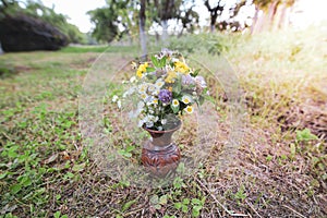Bouquet of colorful wild wild flowers in a broken clay pot laid on the grass