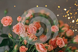 A bouquet of coral-colored roses on a blue background with glitter