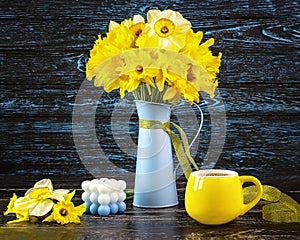 A bouquet of daffodil flowers in a blue vase, a yellow ribbon, a blue candle, a yellow cup of coffee Generated image