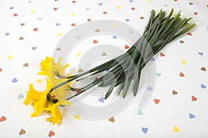 a bouquet of daffodils placed on a tablecloth patterned with multiple colored hearts