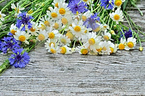 A bouquet of daisies and cornflowers on wooden table