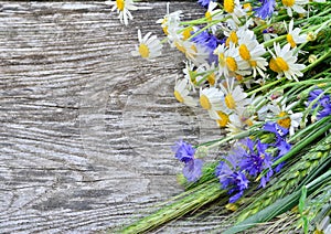 A bouquet of daisies and cornflowers on wooden table