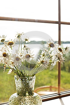 Bouquet with daisies in a vase on a wooden window