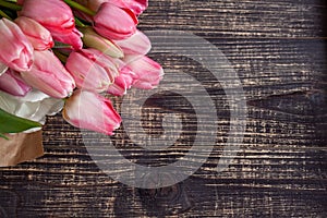 Bouquet of delicate pink and white tulips in paper on a dark wooden background.