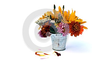 A bouquet of different flowers stands in a small decorative bucket on a white background