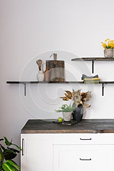 A bouquet of dried flowers and a green plant on the background of the interior of a modern kitchen in the Scandinavian style.