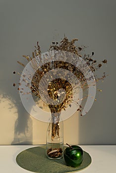 Bouquet of dried flowers on the table in a glass vase, in the light of the sun, contrasting image