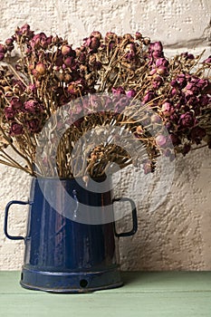 Bouquet of dried roses in blue jug