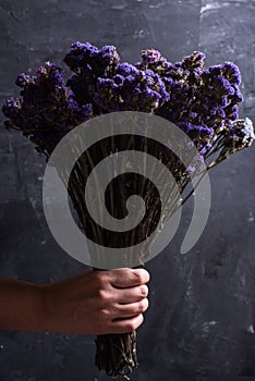 Bouquet of dried wild flowers on a black texture background of vintage wooden planks top view horizontal