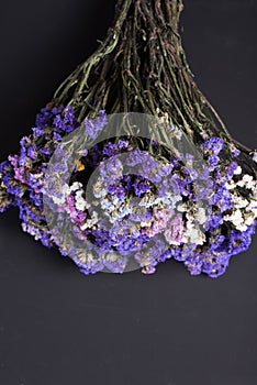 Bouquet of dried wild flowers on a black texture background of vintage wooden planks top view horizontal