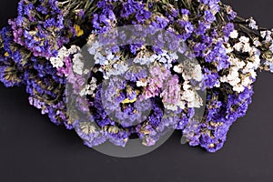 Bouquet of dried wild flowers on a black texture background of vintage wooden planks top view horizontal