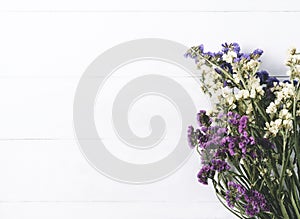 Bouquet of dried wild flowers on white table background with natural wood vintage planks wooden texture top view horizontal