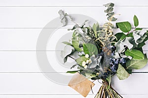 Bouquet of dried wild flowers on white table background with natural wood vintage planks wooden texture top view horizontal