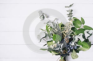 Bouquet of dried wild flowers on white table background with natural wood vintage planks wooden texture top view horizontal