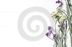 Bouquet of dried wild flowers on white table background  with natural wood vintage planks wooden texture top view horizontal