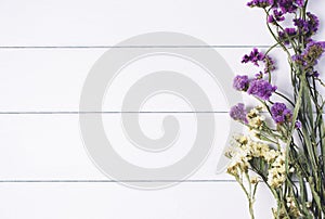 Bouquet of dried wild flowers on white table background with natural wood vintage planks wooden texture top view horizontal, empty