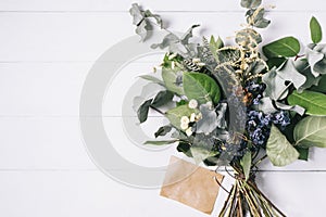 Bouquet of dried wild flowers on white table background with natural wood vintage planks wooden texture top view horizontal, empty