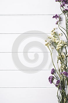 Bouquet of dried wild flowers on white table background with natural wood vintage planks wooden texture top view vertical, empty