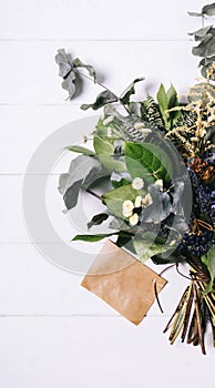 Bouquet of dried wild flowers on white table background  with natural wood vintage planks wooden texture top view vertical, empty