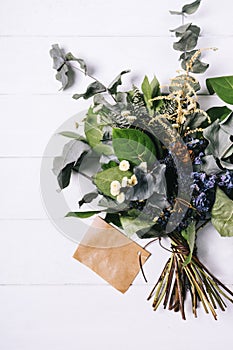 Bouquet of dried wild flowers on white table background  with natural wood vintage planks wooden texture top view vertical, empty