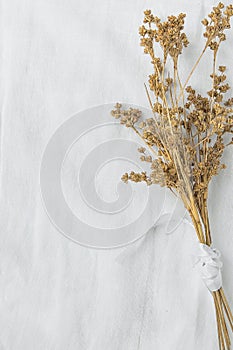 Bouquet of Dry Beige Brown Flowers Tied with Silk Ribbon on White Linen Fabric Background. Japanese Style. Easter Mother`s Day.