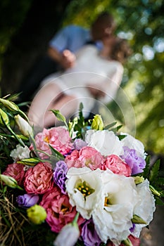 bouquet of eustoma and roses and kissing couple on the soft background